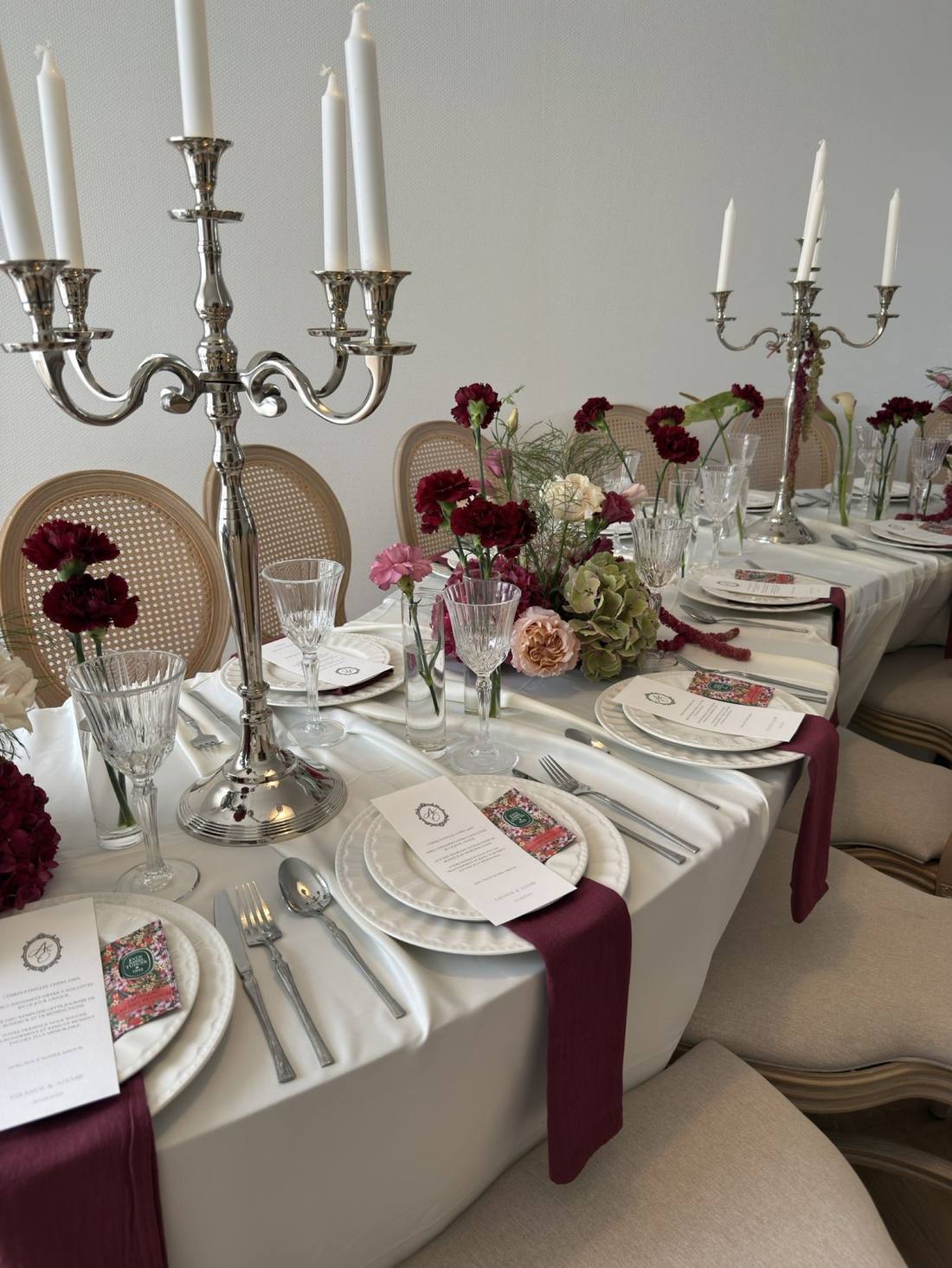 Table dressée, candélabres argentés et œillets bordeaux